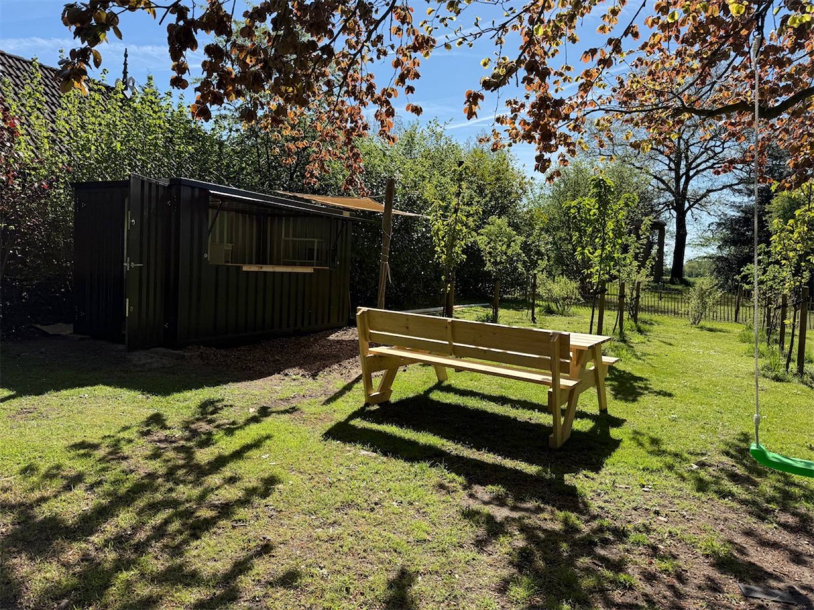 Houten bankje in de zon naast onze koffiebar in de fruitboomgaard
