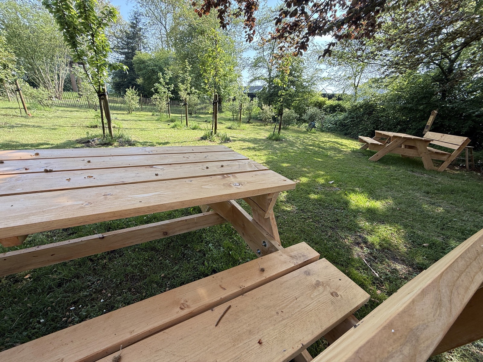 Nieuwe houten picknicktafels met rugleuning in de boomgaard